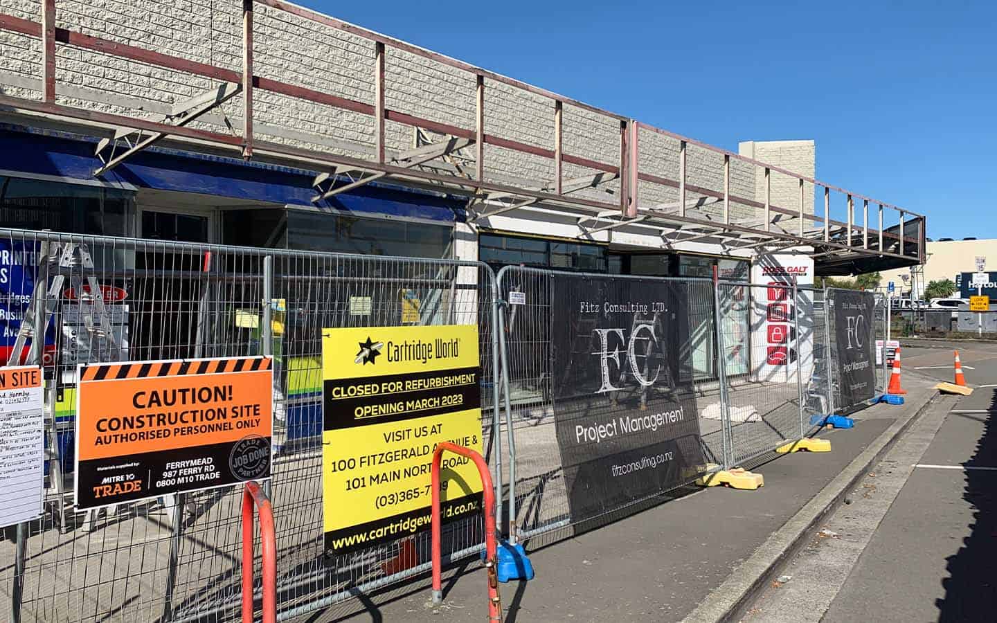 The front of a commercial building with retail stores under renovation